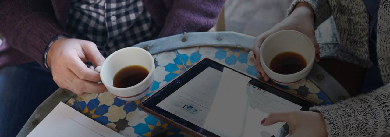 Una pareja tomando café, viendo el sitio web de Amway en una tableta. Conoce lo que otras personas dicen sobre nuestra oportunidad de negocio Amway.