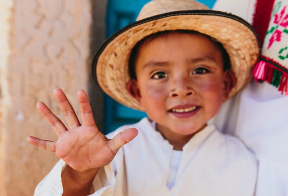 Un niño levantado su mano derecha por el programa Cuenta con 5 de Nutrilite. Amway lucha contra la desnutrición infantil a nivel global.