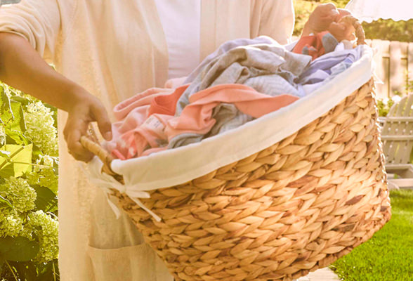 Imagen de una mujer levantando una cesta de ropa limpia. Descubre cómo Amway Home simplifica tu vida.