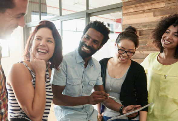  Imagen de cinco personas sonriendo y uno de ellos sostiene una tableta. Descubre el programa de recompensas Amway.