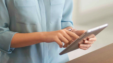 La imagen de fondo muestra a una mujer interactuando con una tableta.