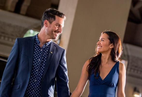 Imagen de una mujer y hombre vestidos de azul, sonriendo mientras ingresan a un evento. Reconocemos tu esfuerzo y tu logro como Diamante.